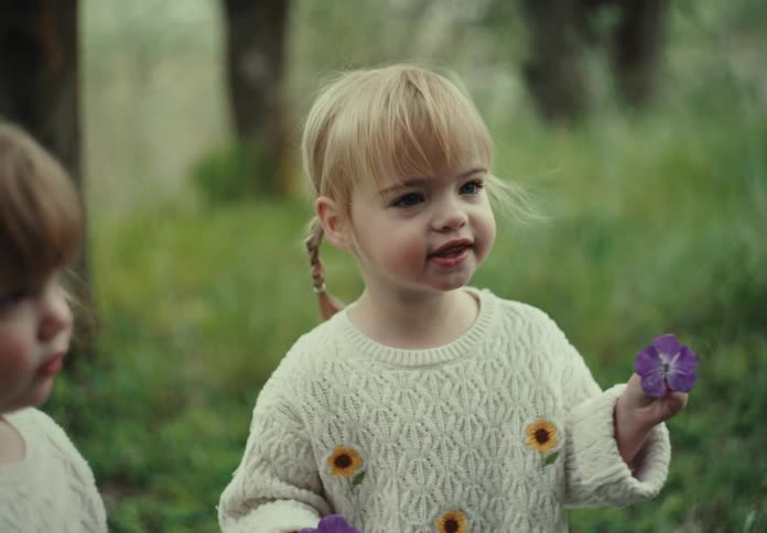 A mother puts a flower on her ear to her daughters amusement