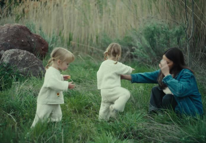 Mother sitting on the grass with her two little twin daughters