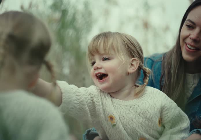 A mother smiles while watching her two daughters play together