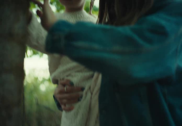 A mother and her two daughters touch the bark of a tree in a forest
