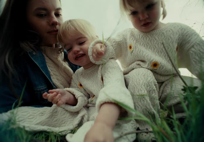Children play in the grass as their mom watches