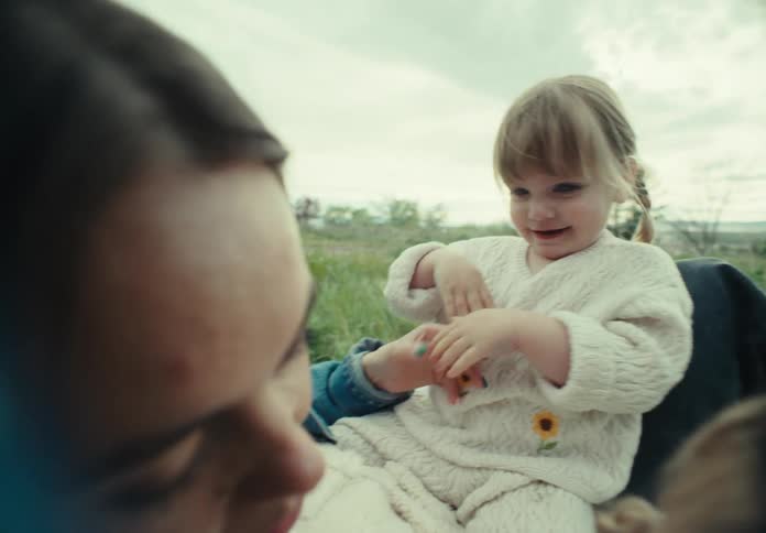 A mother and her two children laugh and play out in nature