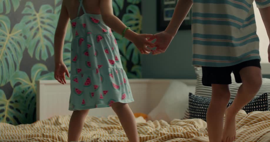 A little boy and a little girl are holding hands and walking on a bed