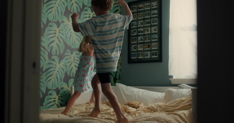 Two children playing on the bed in a room