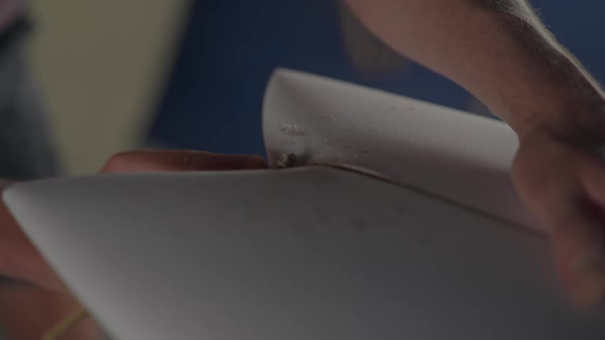 Sewup of a persons hands handling a tool and scraping material