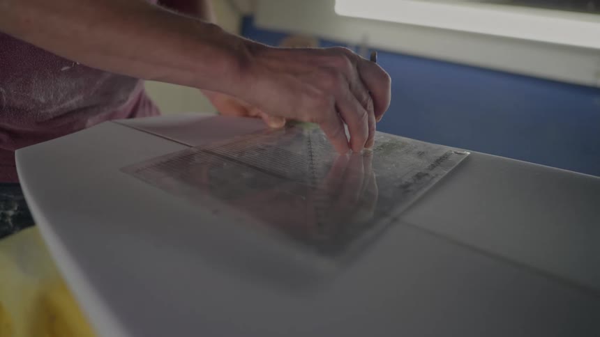 Man using a ruler in measuring a surfboard