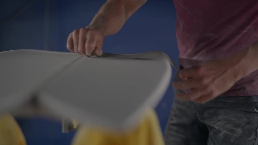 A carpenter carefully sands white pieces of wood