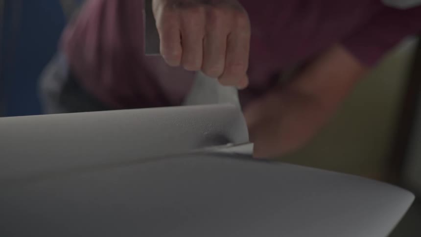 Man sanding the edge of a piece of furniture with a loose sheet of sandpaper