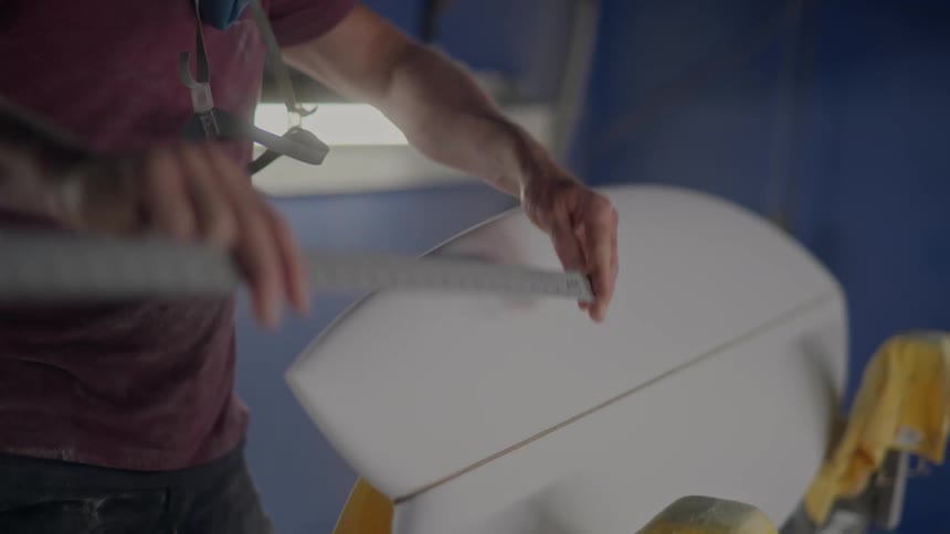 Pair of hands with a ruler measuring the length of a surfboard