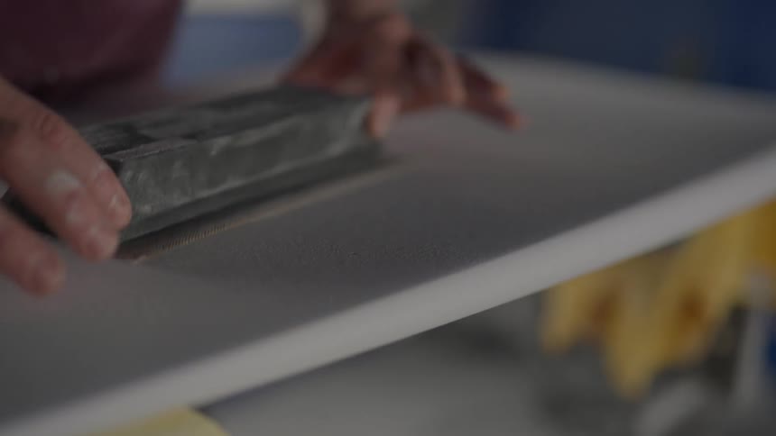 Hands sanding a white board
