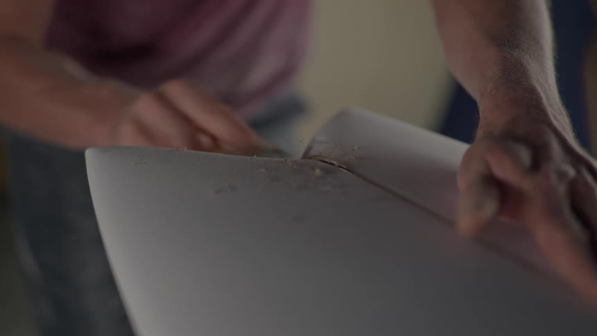 A man files away at a seam between two pieces of wood