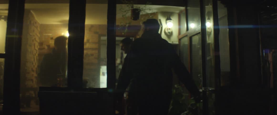 Two men walk into a home and greet friends at night