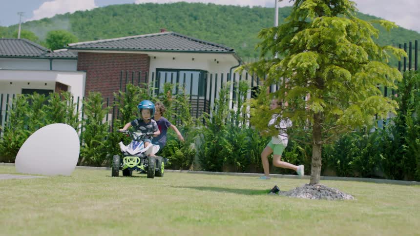 Three kids play together in a park with a giant egg stuck in the ground