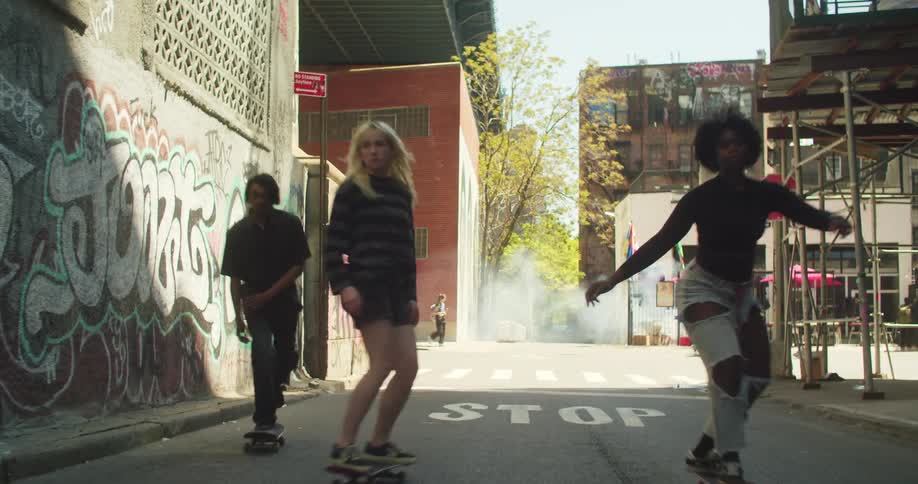 Three teenagers skateboard off a busy city street