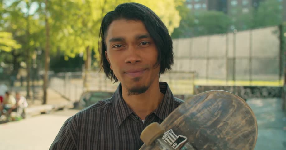 Portrait of a young man in a skate park holding a skateboard in his hand