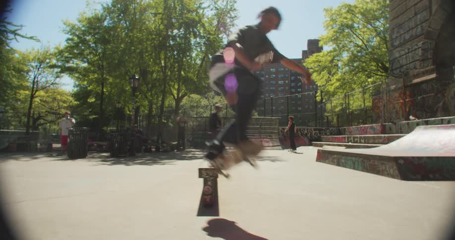 A guy performs a jumping move with his skateboard in a park in the city