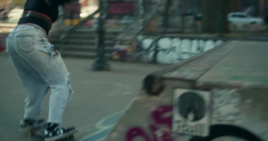 A black girl rides a skateboard up and down a concrete ramp doing tricks
