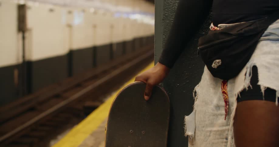 Hand holding a skateboard in a subway station