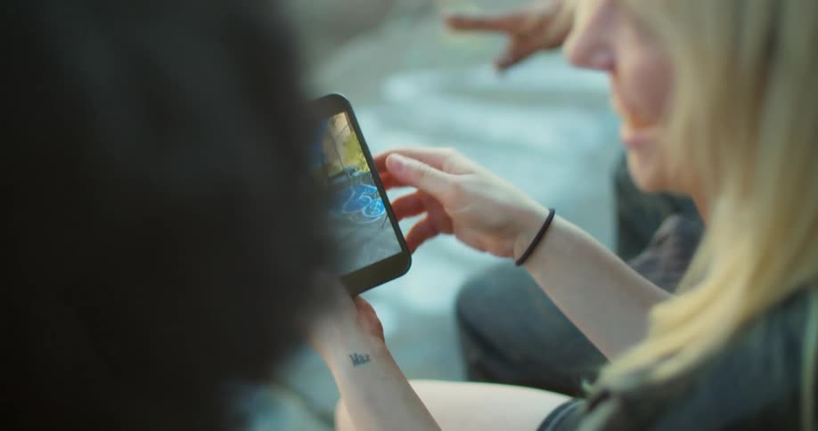 Three skateboarders watching videos of themselves on a smart phone