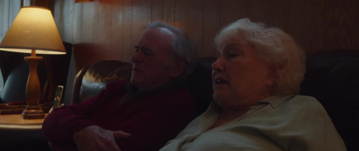 A husband and wife talk while sitting on a couch