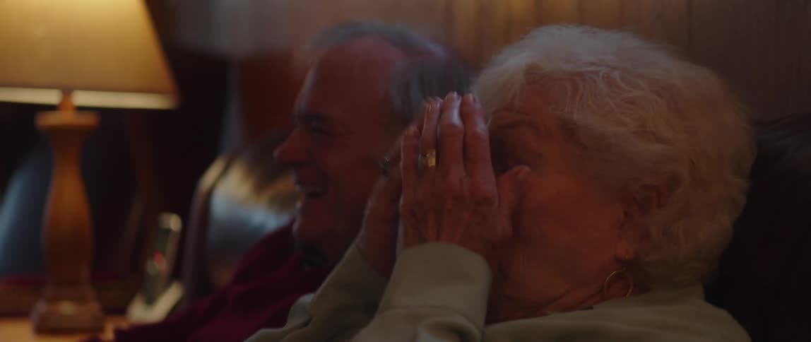 A man and woman laugh and react to something