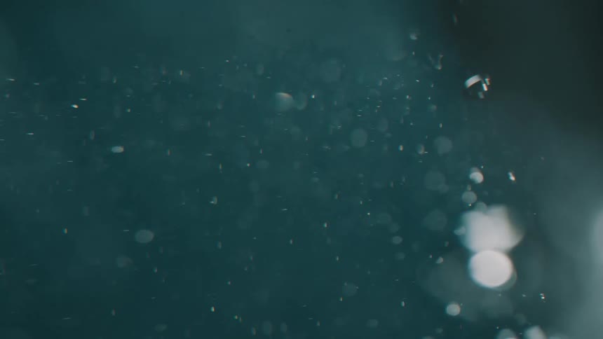 Floating particles swirl as bubbles are created when the water is disturbed