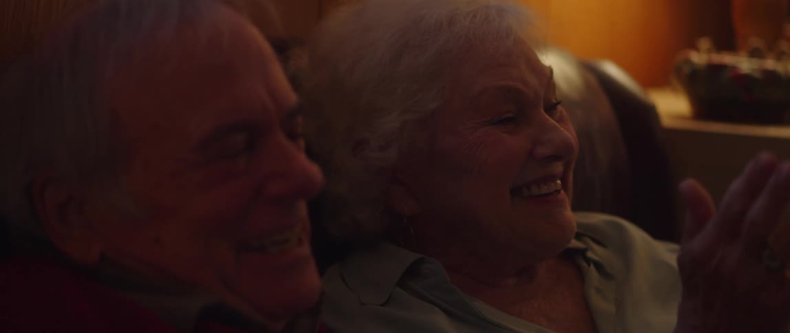 Elderly couple sitting on the couch watching and laughing