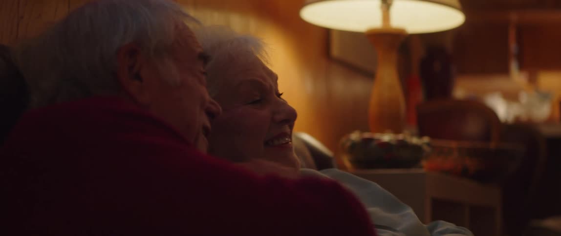 Laughing elderly couple sitting on the couch watching tv