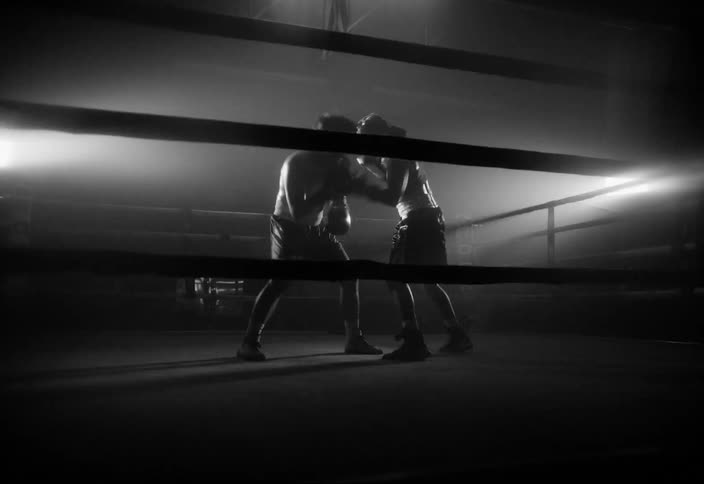 Two people boxing in a ring illuminated by a diffuse light