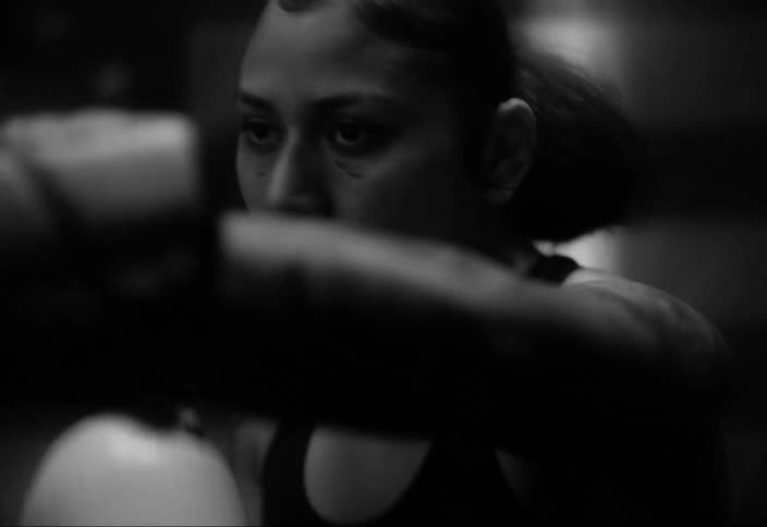 A latina boxer throws punches while standing in front of an american flag