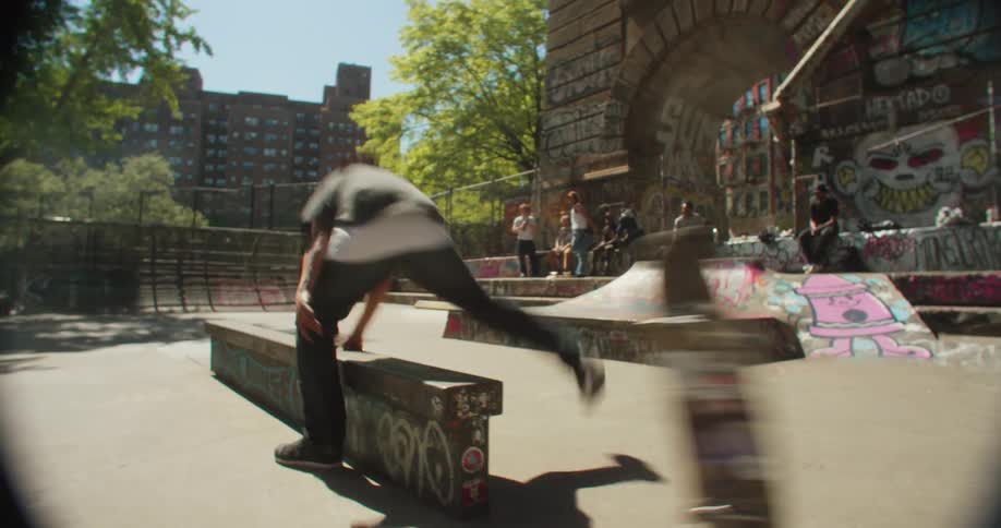 A young male skater falls after performing a trick on a grind rail at a skate park