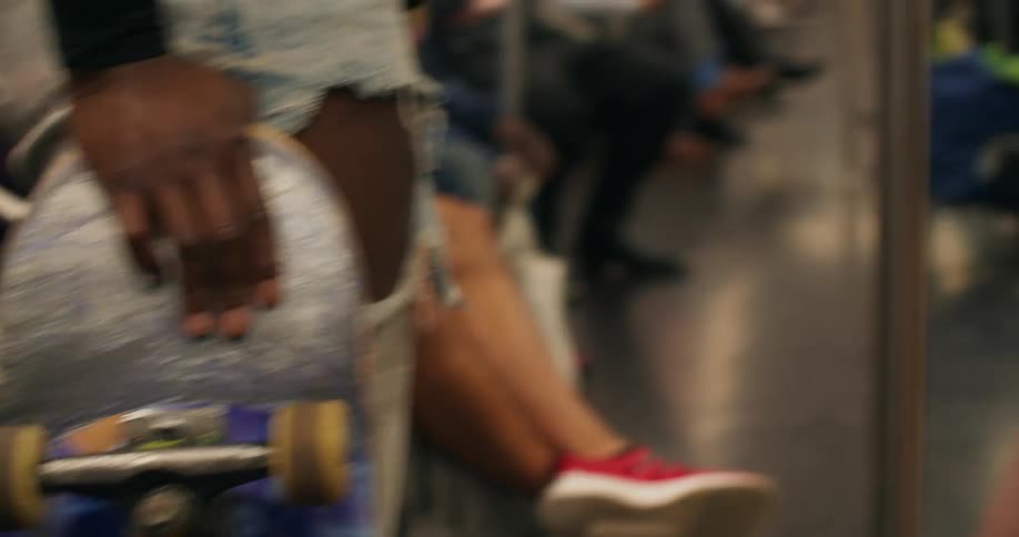 Two females hold their skateboards while riding a subway