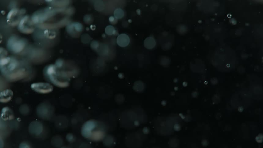 Several bubbles going up in a dark underwater environment