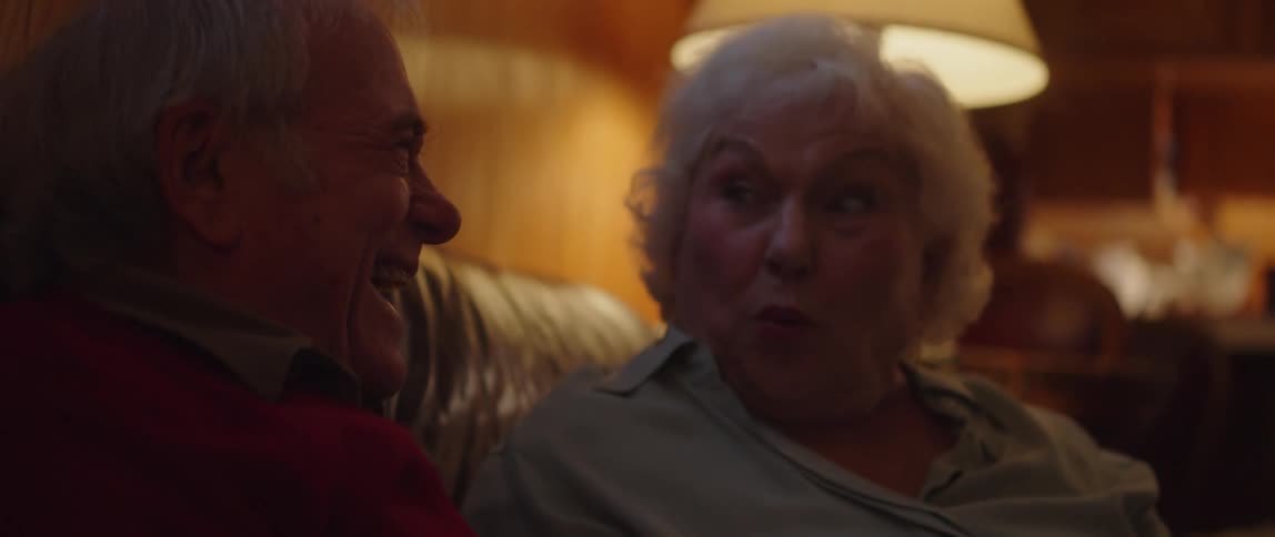 Elderly couple sitting in an armchair watching and laughing together