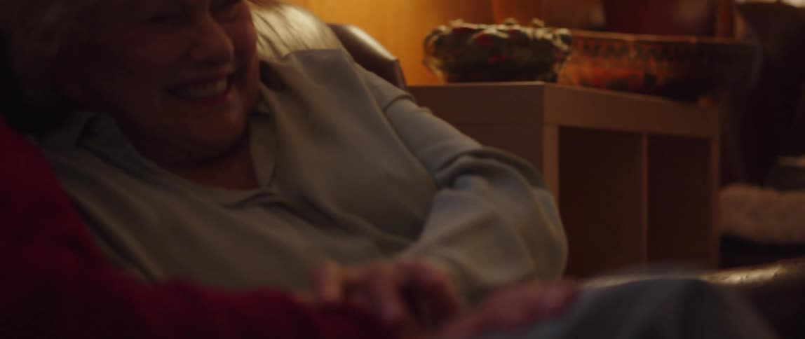 Elderly man and woman cuddle at home while enjoying an entertainment together