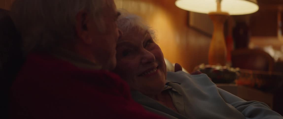 An elderly couple watches a movie together in their home