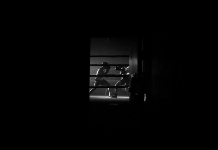 Silhouette of two people in a ring fighting boxing