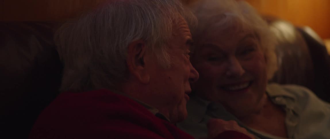Close up of an elderly couple laughing while watching tv