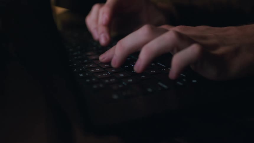 A white male types on a laptop keyboard