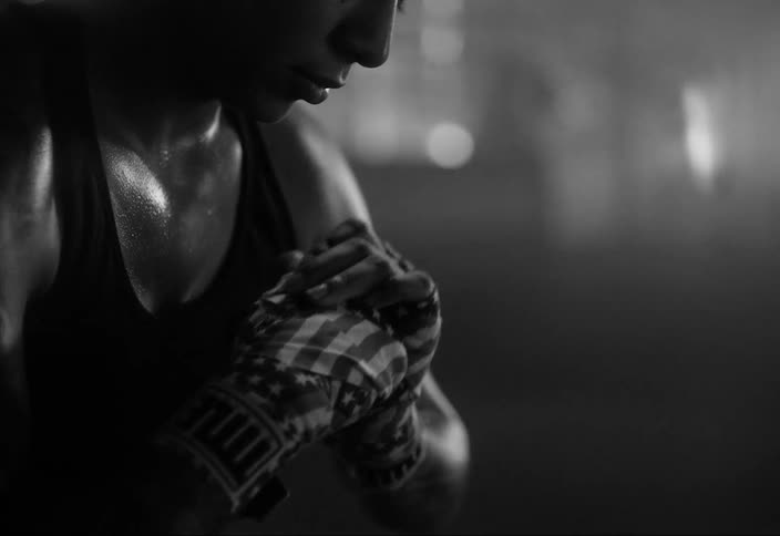 A sweaty man with gloves cracking his fingers while flashes of photos flash at him and everything is in black and white tones
