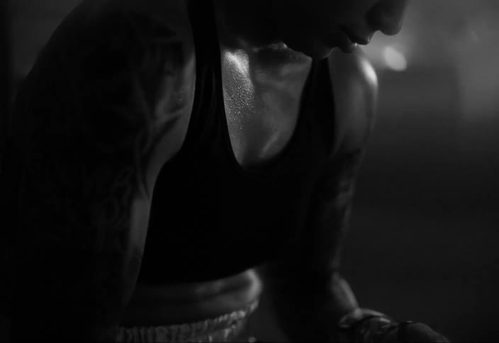 Woman with a sweaty body adjusting her boxing gloves
