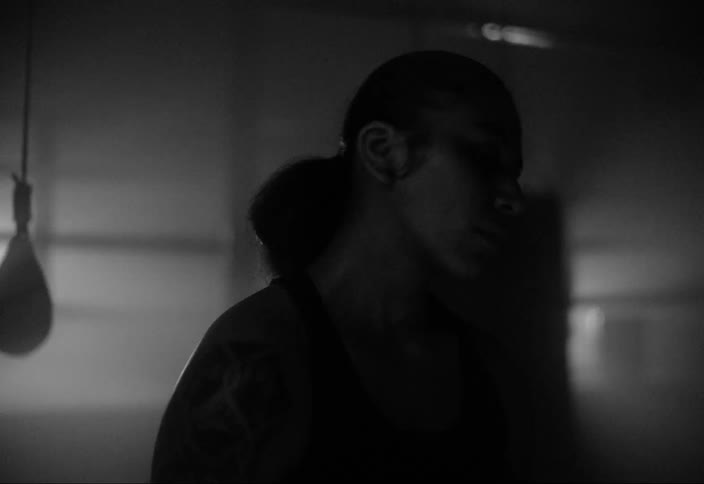 A woman with tattoos shakes her head from side to side in a gym