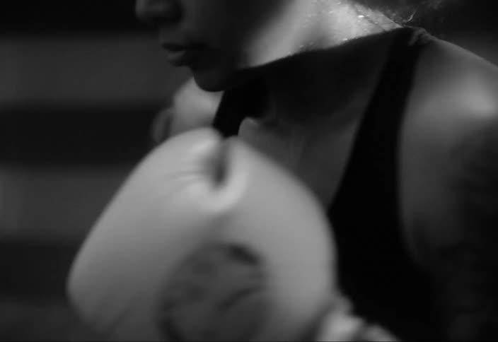 Sweaty woman throwing punches with boxing gloves in a workout