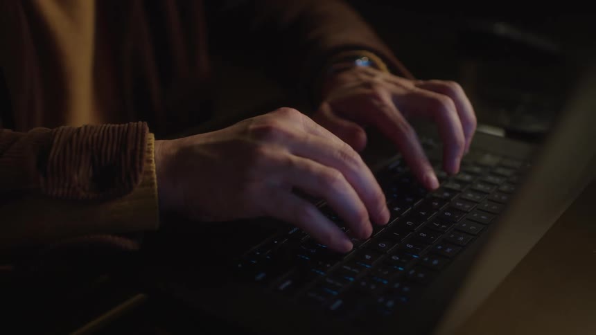 Hands of a person typing on a laptop keyboard