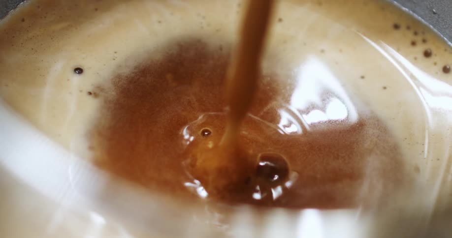 Coffee is slowly poured into a cup