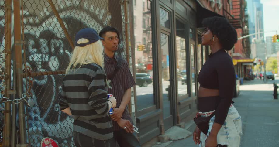 Two women talk to a man downtown on a sunny day
