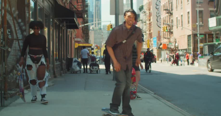 Three friends on a city sidewalk riding skateboards