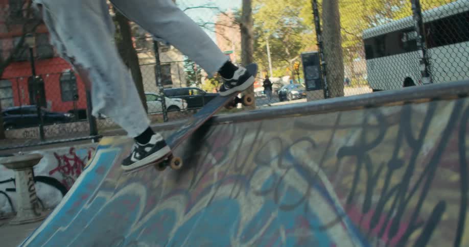 The legs of a person skateboarding up a graffiti ramp and then back