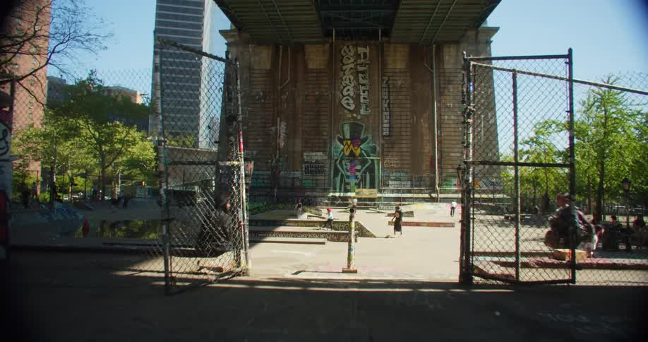 Group of people walking and skateboarding in a square below an overpass