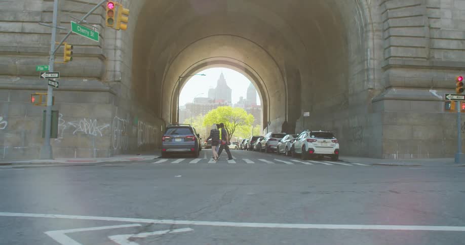 Three friends crossing a street and walking on the sidewalk in New York City as cars pass by